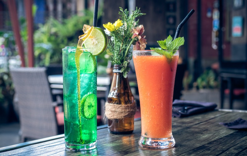 two vibrant drinks served in glasses on an outdoor table