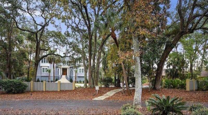 Residential building with multiple windows and balconies among green trees, near the Palmetto Dunes lagoon system.