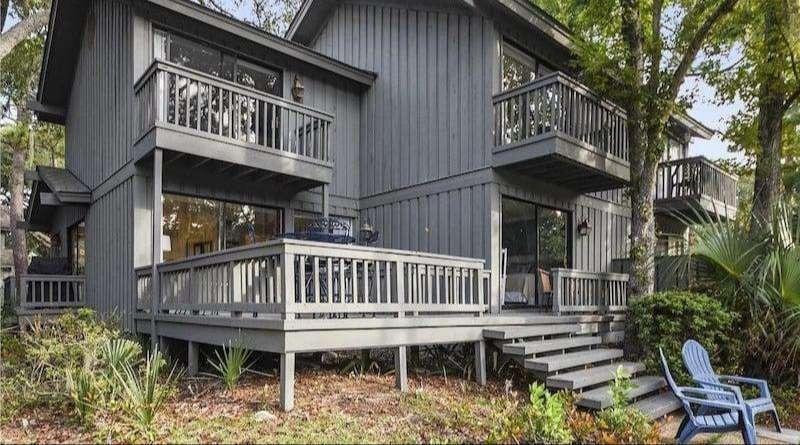 Exterior view of three-story, brown villas surrounded by lush green trees, part of the Moorings complex.