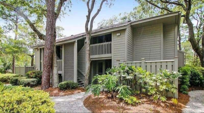 Multi-story villa with several large decks and white railings overlooking a tree-filled area.