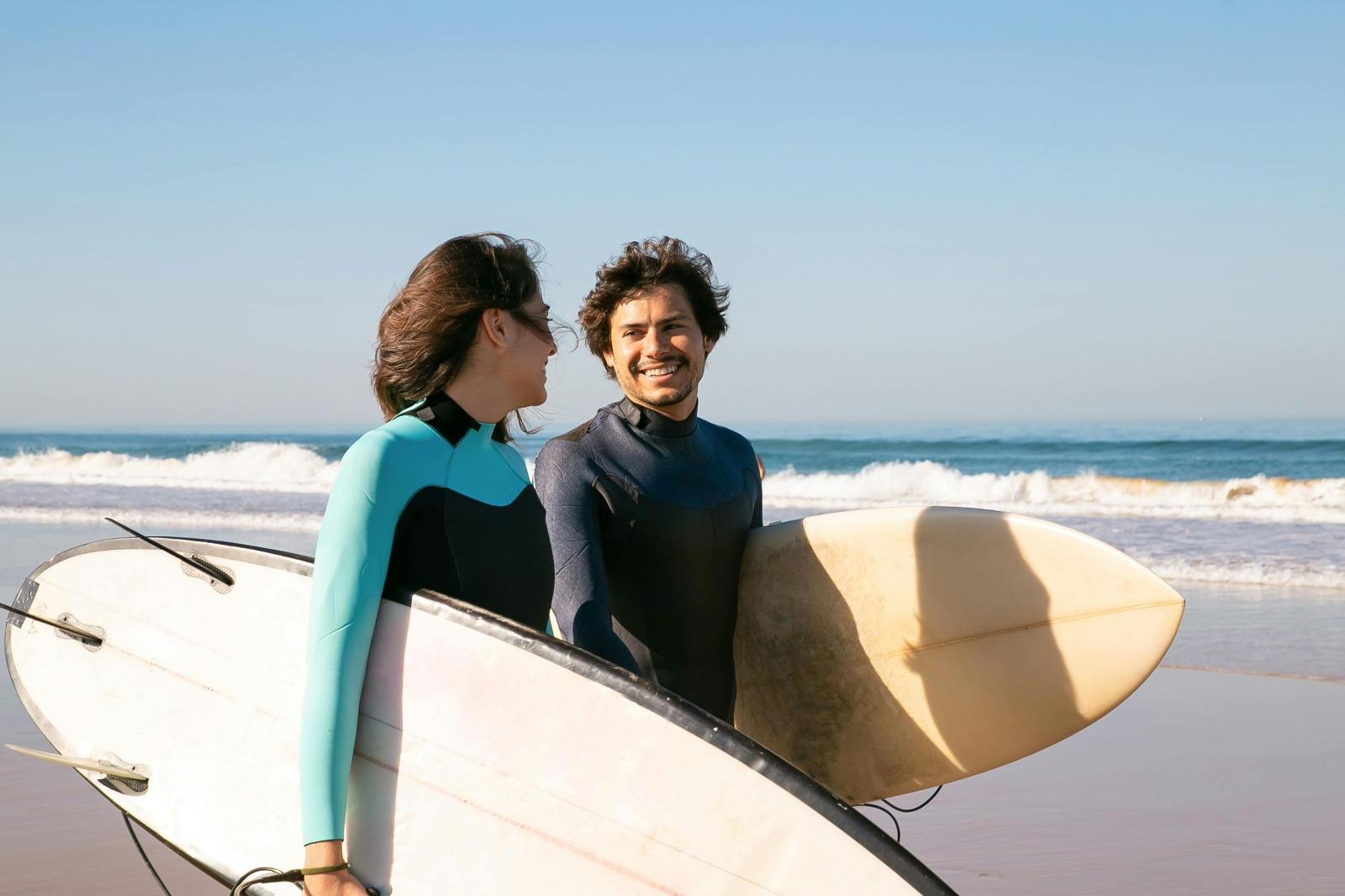 A happy surfer couple smiling at each other on the beach